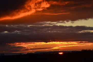 Fototapeta premium Sunset, golden, orange, red clouds, against the dark sky.