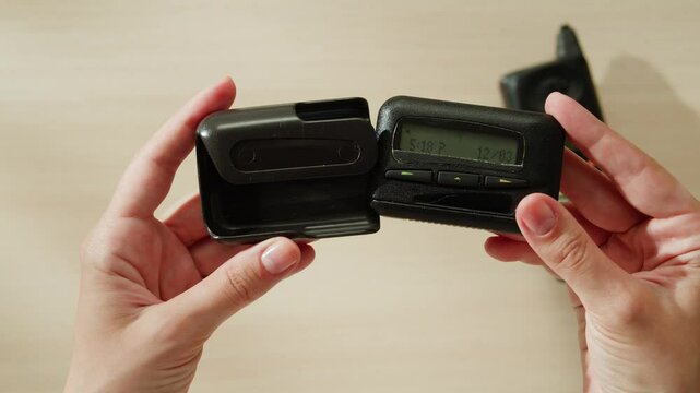 Pager beeper device close up on a desk, retro phone 90s instant communication and connection, sms messaging in the early 80s 90s digital age