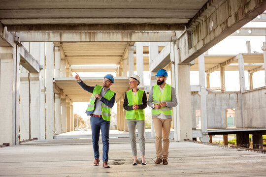 Team of successful young architects and business partners checking work progress on a construction site. Architecture and teamwork concept.