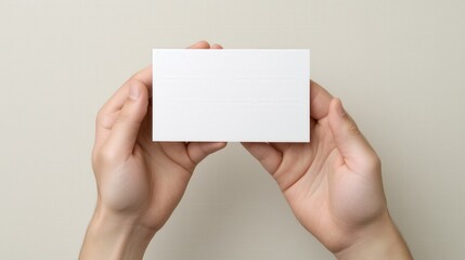 Fototapeta premium two Hands Holding Blank White Card with fingers visible around the edges