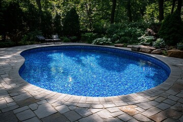 Kidney shaped swimming pool surrounded by lush greenery and stone patio