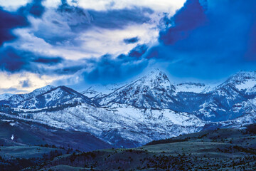 2023-12-31 MOODY SNOW COVERED ABSAROKA MOUNTAIN RANGE IN MONTANA WITH THE LOWER RANGES EXPOSED AND A CLOUDY SKY
