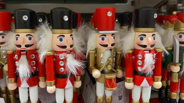 Nutcracker toys are lined up on a store shelf. Nutcracker soldiers in uniform bring holiday charm to the store. Nutcracker toys, alongside Christmas ornaments, create a festive atmosphere.