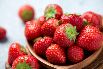 Group of fresh strawberries on a wooden plate, closeup view