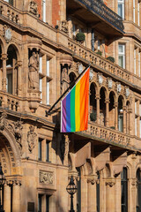 A vibrant rainbow flag, symbolizing LGBTQ+ rights and equality, hangs proudly on a historic building in London, UK. This image captures the spirit of diversity, inclusion, and celebration of identity