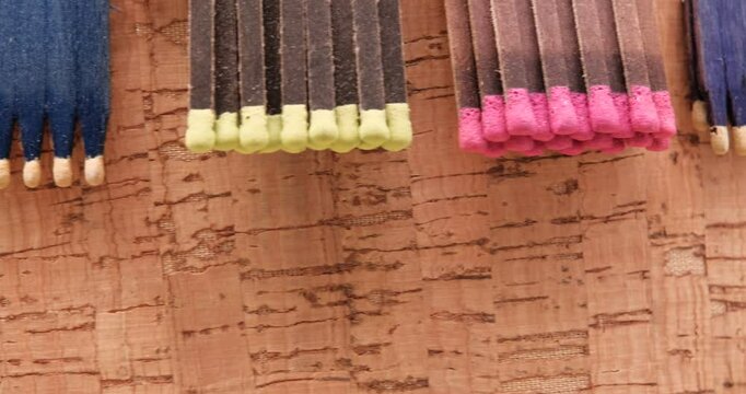 matchsticks of various shapes and colors on a rotating table with Texture of cork board wood surface on background