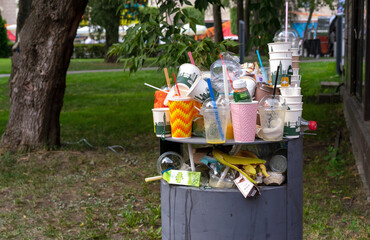 Full garbage bin on a street in the city. Concept of garbage pollution in large cities.