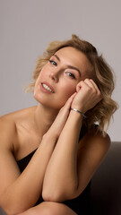 Fototapeta premium Confident Woman with Short Wavy Hair Wearing a Stylish Black Outfit in a Studio Setting