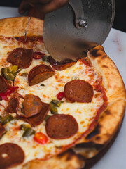 A close up shot of pizza with pepperoni on a plate with a pizza cutter