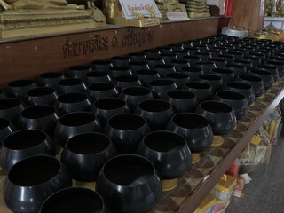 Monks' alms bowls are arranged in a Thai temple.