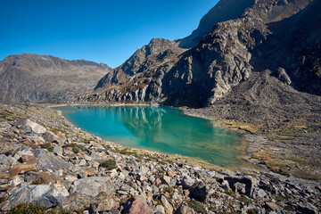 Obraz premium Serene turquoise lake surrounded by mountains under a clear blue sky in a remote wilderness area