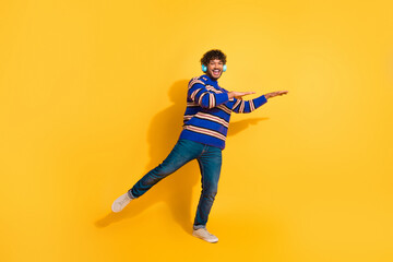 Fototapeta premium Full size photo of pretty young male headphones dancing wear stylish blue striped outfit isolated on yellow color background