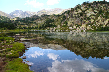 Watched over by the Pic Carlit, the rocky banks of the Bailleul lake are reflected in its clear waters on an August afternoon (Pyrénées Orientales, France)