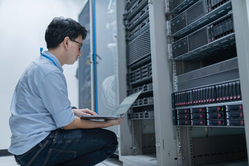 Computer engineer is setting up network in server room,Systems Maintenance Technician,Male engineer working in server room at modern data center