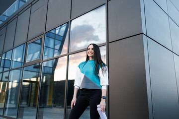 Woman holding bottle with water after morning workout. Young athletic woman standing near dark wall background after jogging Healthy lifestyle concept