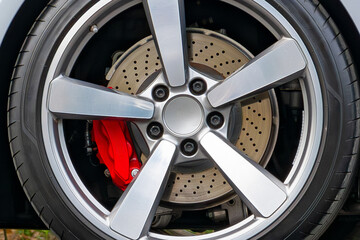 ventilated sports brake disc of a passenger car with a red caliper and brake pads. close-up
