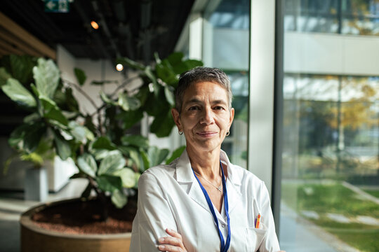 Confident female doctor portrait standing in hospital with plants in background