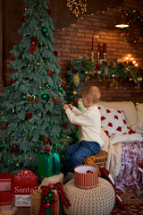 Cute little girl hanging ornaments and balls on Christmas tree. Kid decorating Christmas tree.