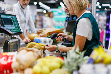 Cashier scanning groceries at supermarket checkout counter