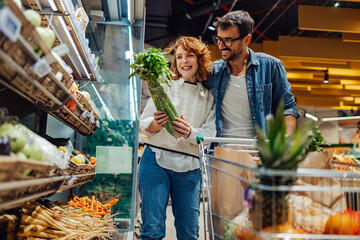 Happy couple choosing fresh produce while grocery shopping at supermarket