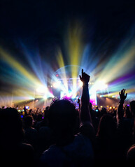 Young man with his hands in the air watching a concert at night