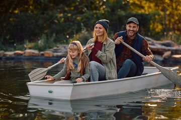Happy family rowing along lake in autumn day.