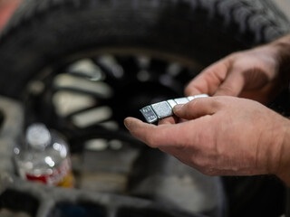 A mechanic attaches balancing weights to a wheel. 