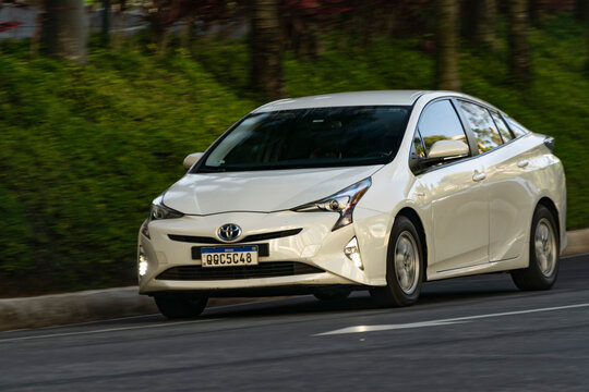 White Toyota Prius in movement, Panning shot of hybrid sedan in city street, High Resolution