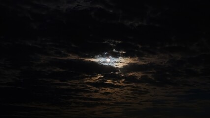 The full moon shines through the clouds.