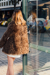 une femme de dos avec un manteau de fourrure attendant le bus. Belle femme de dos avec une lumière...