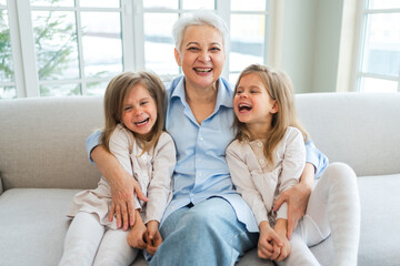 Happy family at home. Two little girls sisters twins grandmother enjoying time together. Good time at home. Grandma granddaughters child kids emotional bonding hugging together. Family generations