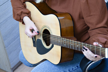Fototapeta premium Female hands on the guitar. Close-up guitar fragment