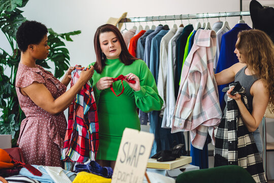 Girls having fun at home swap party. Garage sale, second hand, trying used clothes, exchanging jeans, dresses, accessories . Sustainable fashion, conscious consumption, circular economy concept