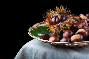 Chestnuts with leaves and burs on a wooden table