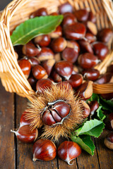 Chestnuts with leaves and burs on a wooden table