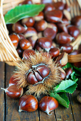 Chestnuts with leaves and burs on a wooden table