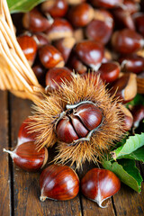 Chestnuts with leaves and burs on a wooden table