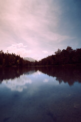 Calm lake reflecting mountains and sky during golden hour in a serene landscape