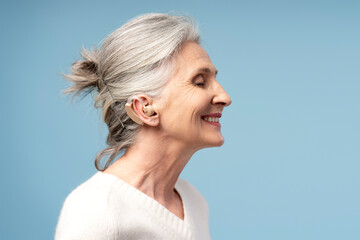 Portrait of smiling, beautiful senior woman having hearing aid, with closed eyes