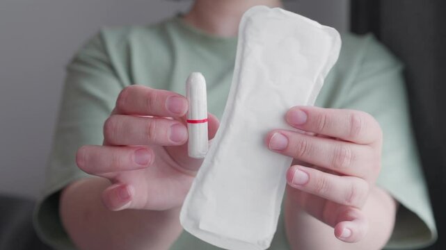 woman hands holding pad and tampon making decision of hygienic products. Different types of feminine menstrual hygiene materials 