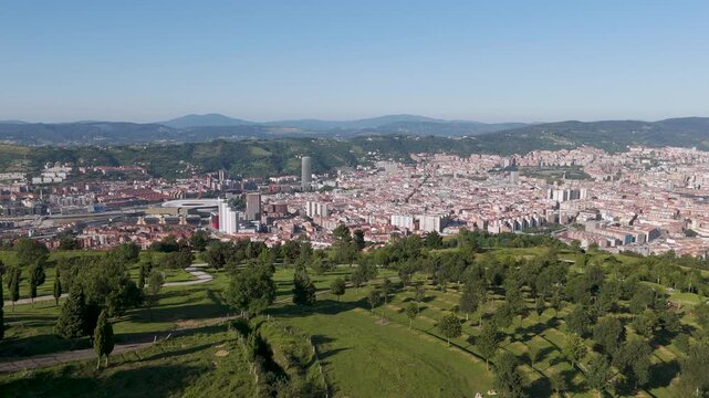 Drone footage of the green Mount Cobetas and the cityscape of Bilbao on a sunny day in Biscay, Spain