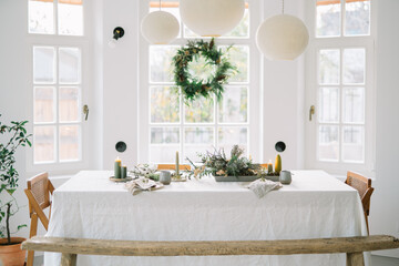 Bright dining room with festive table setting and wreath.