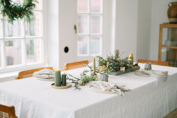 Candle-lit table setting with winter greenery decor.