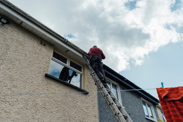 Man Fixing Gutters on a Ladder