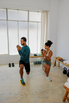 Personal trainer showing correct posture doing lunges with weights