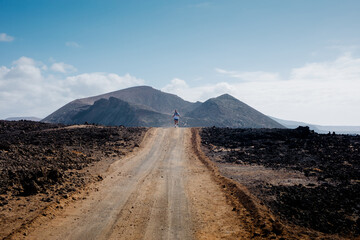Broad-angle view captures a fit man trekking through volcanic terrain