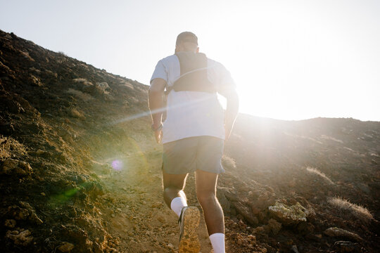 Outdoor trail running enthusiast sprints up a steep volcanic trail