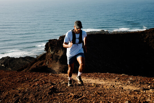 Athletic man climbs a steep, narrow trail, running uphill