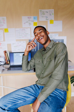 Young web designer smiling and thinking in his office