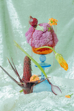 Vibrant vegetable arrangement on a decorative stand in soft lighting.